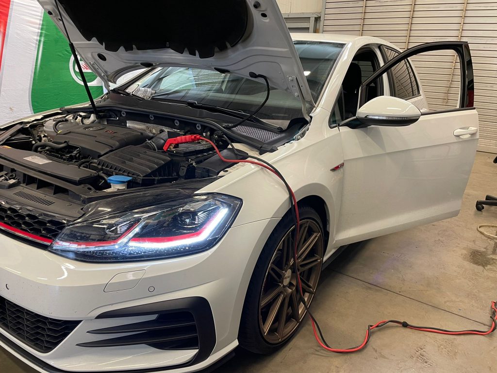 weißes Auto mit offener Motorhaube beim Tuning in der Werkstatt